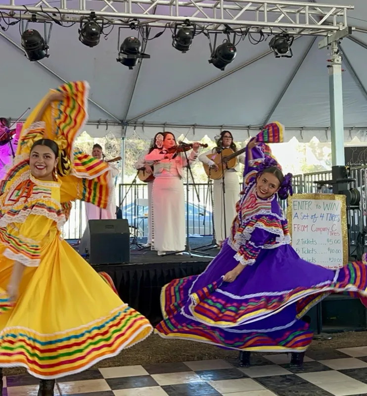 Ballet Folklórico Mi Herencia dancers performing with live mariachi under a tent